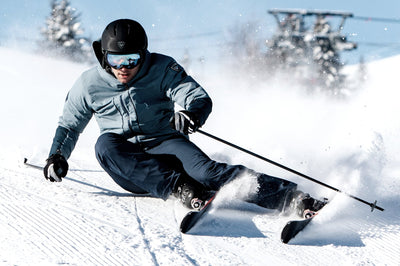 Power Ski - Mann mit Skibrille und Skihelm schwingt auf Sport Carvern auf Kamera zu