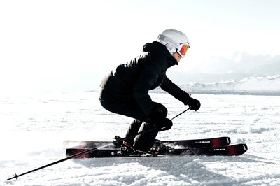 Power Ski - Frau mit Skihelm und schwarzer Skijacke fährt mit Race Carvern auf Piste