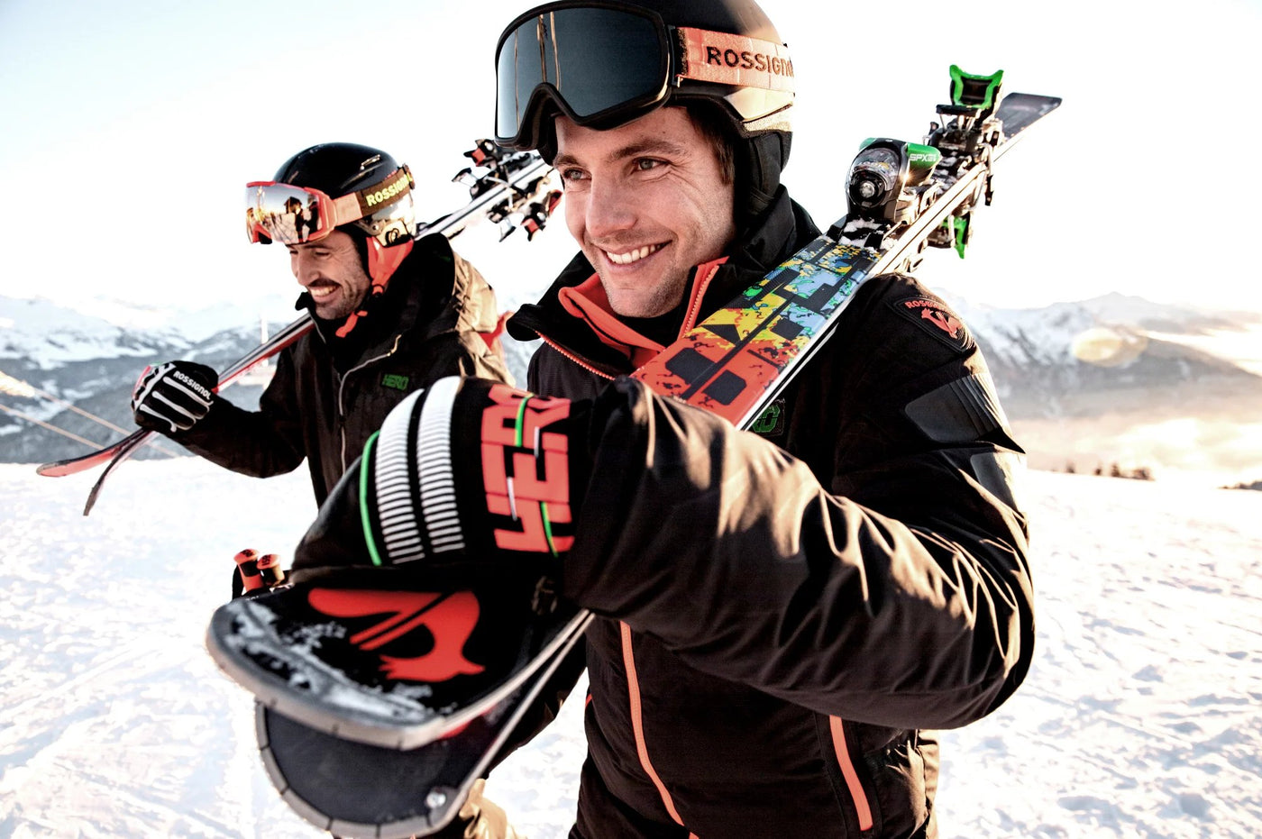 Power Ski - Zwei Männer tragen Alpin Ski auf den Schultern und lachen