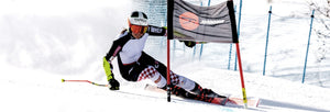 Power Ski - Frau mit Skihelm und Rennanzug umkurvt Tor